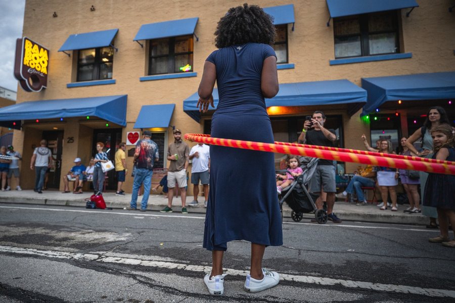A woman watches a hula hoop performer on the street at MangoFest, Lake Worth Beach