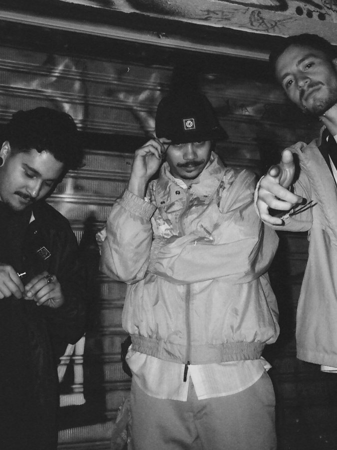 Three Medellín rappers posed against a shutter, black and white film