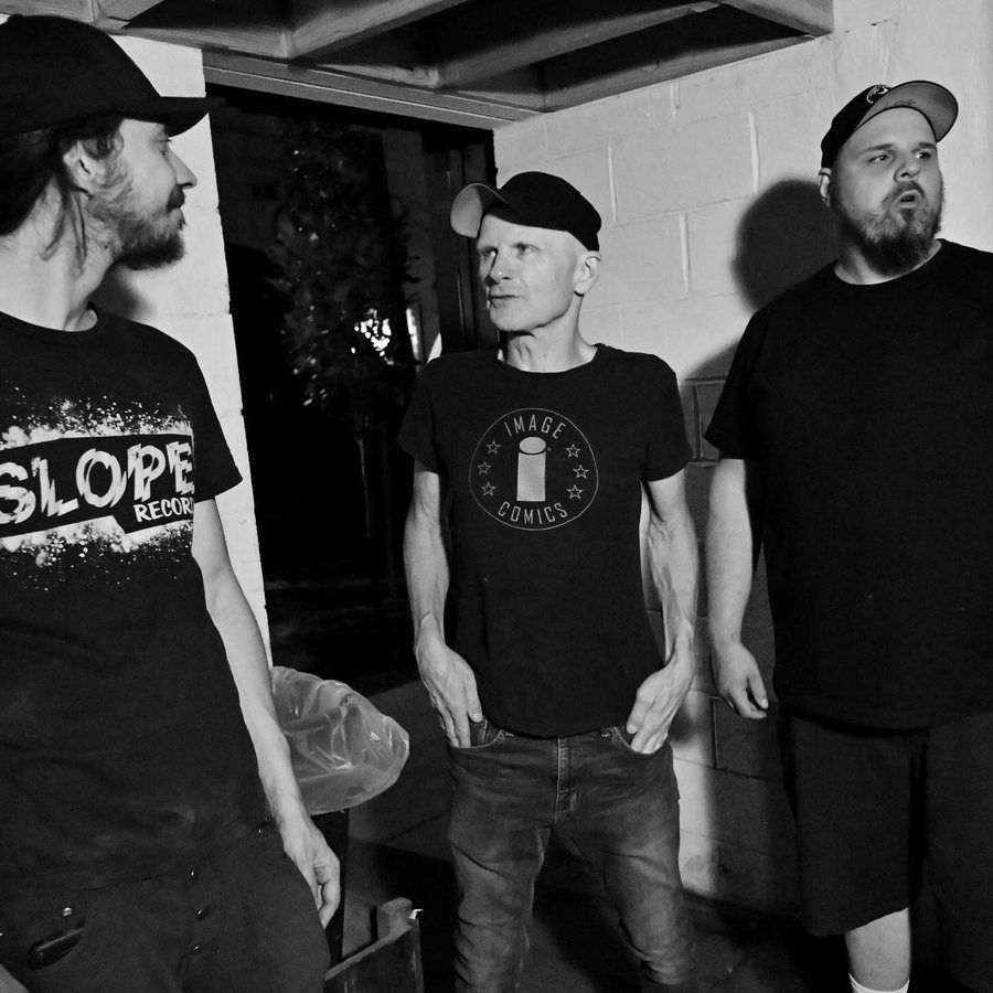 Three band members posed in a doorway, black and white